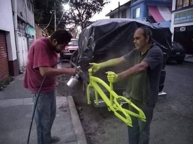 guy spray painting a bike frame that another guy is holding