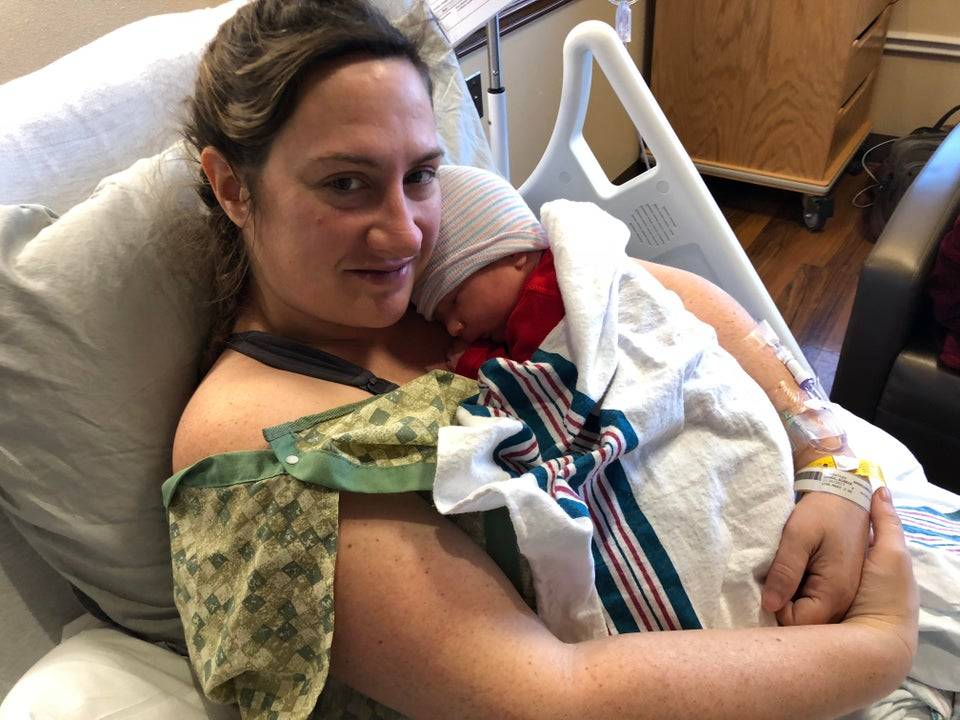 woman carries new born baby in hospital bed