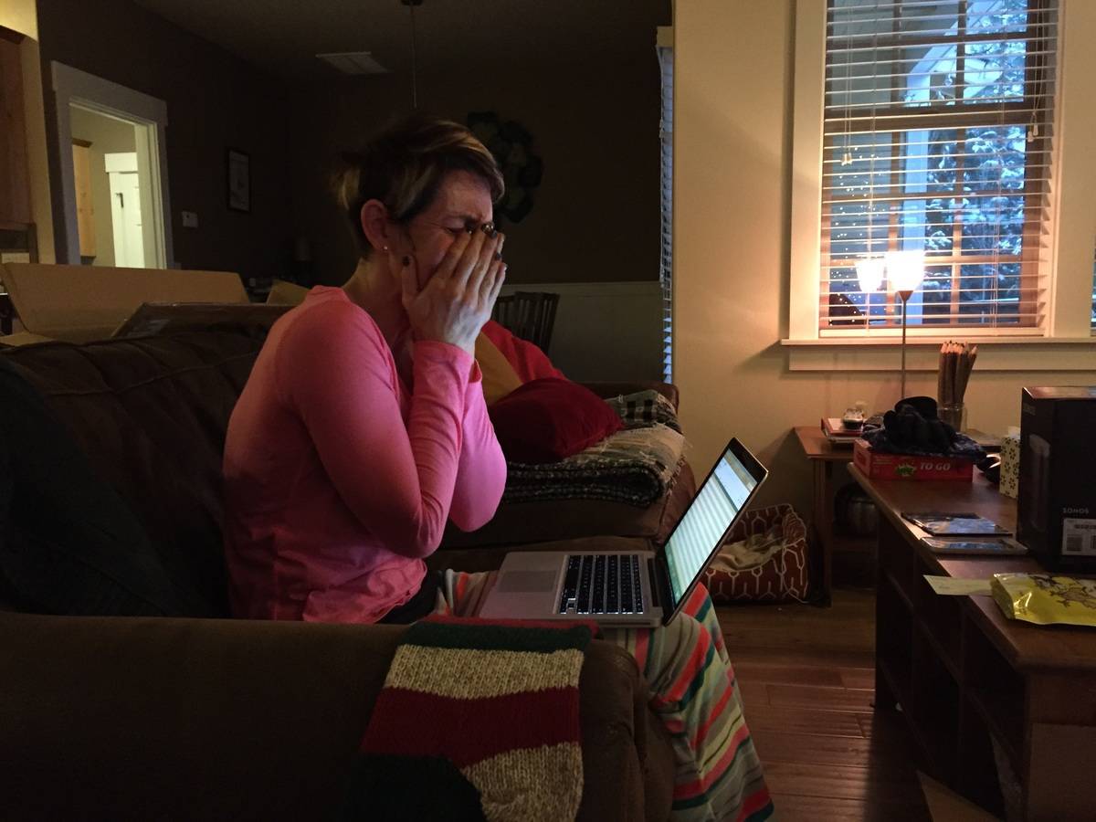 woman crying at laptop while sitting on the couch in pjs