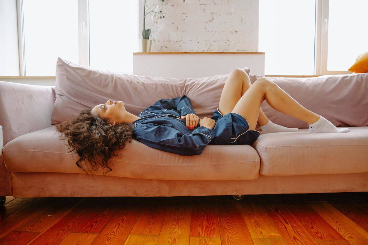 woman lying on couch holding abdomen in pain