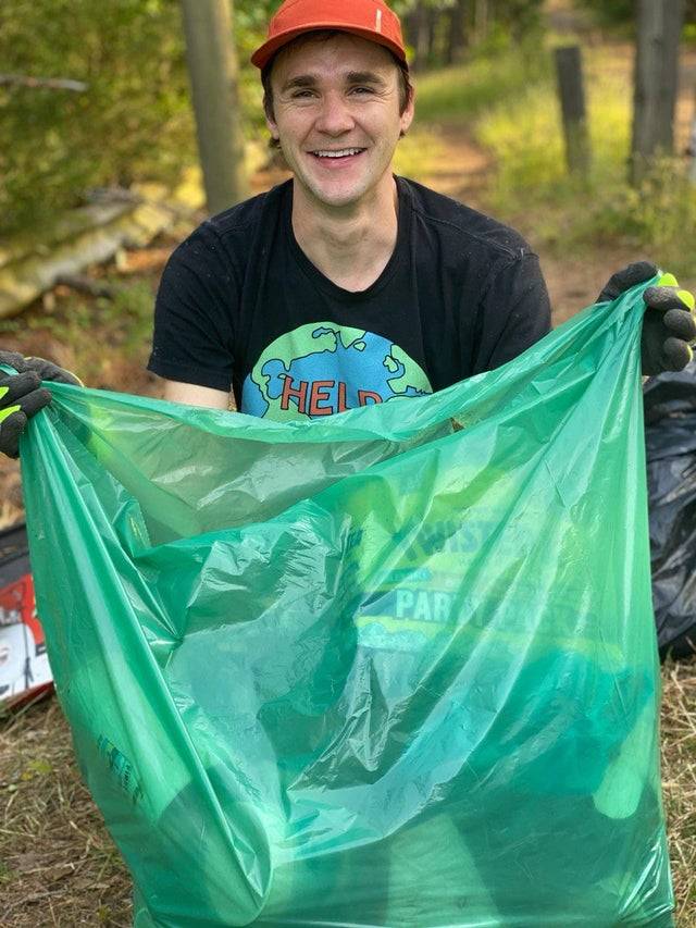 man with trash bag picking up 7000th bag of litter in life
