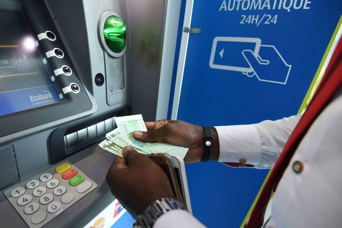 A well-dressed man takes money out of an ATM.