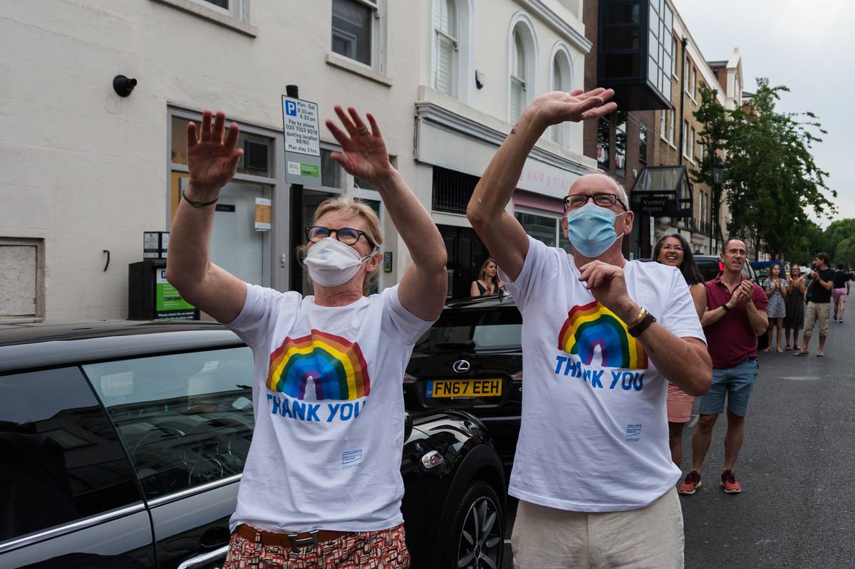 Local residents wearing matching rainbow t-shirts wave their hands outside Chelsea and Westminster Hospital