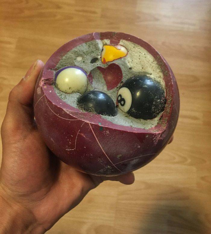 Broken bocce ball is filled with pool balls and concete