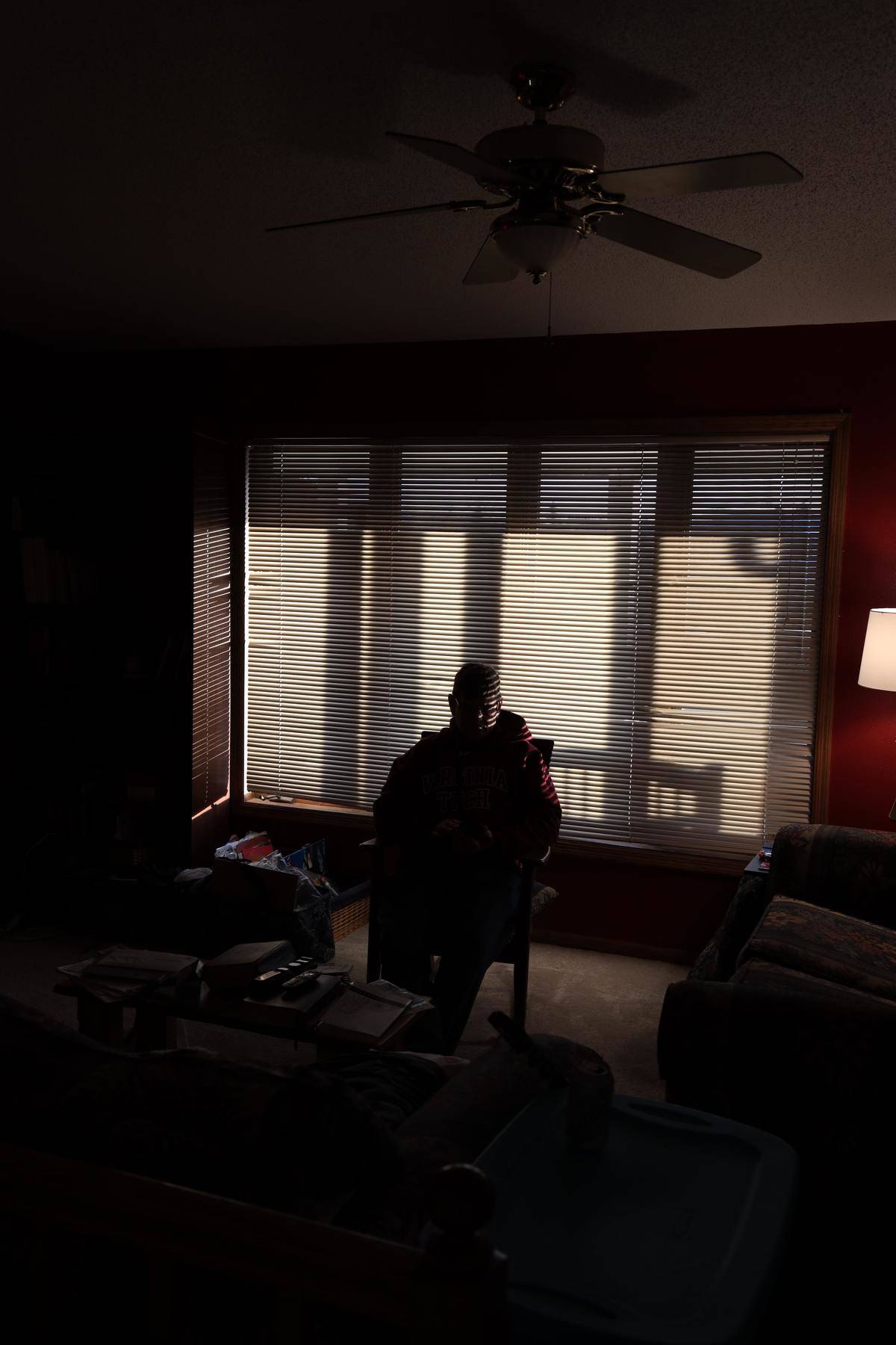 man sitting in dark room with the blinds closed