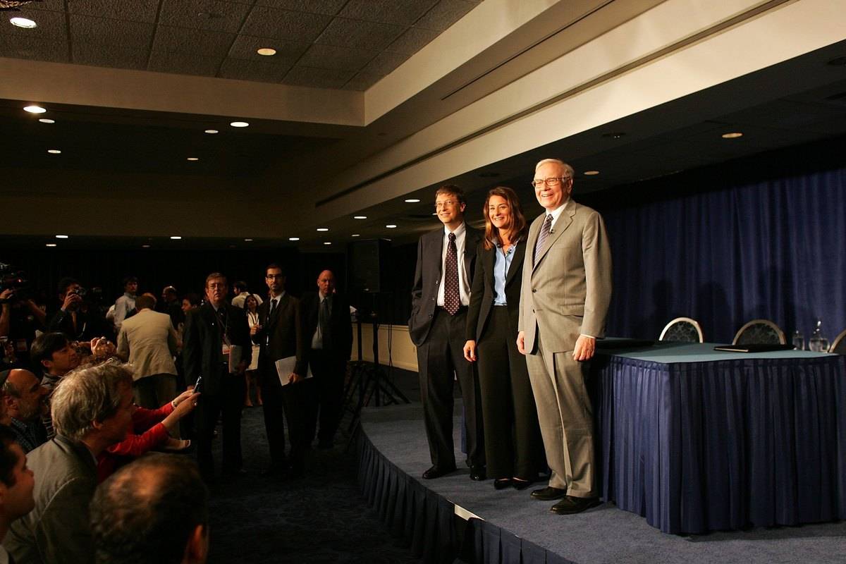 Warren Buffett stands next to Bill and Melinda Gates onstage during a charity event.