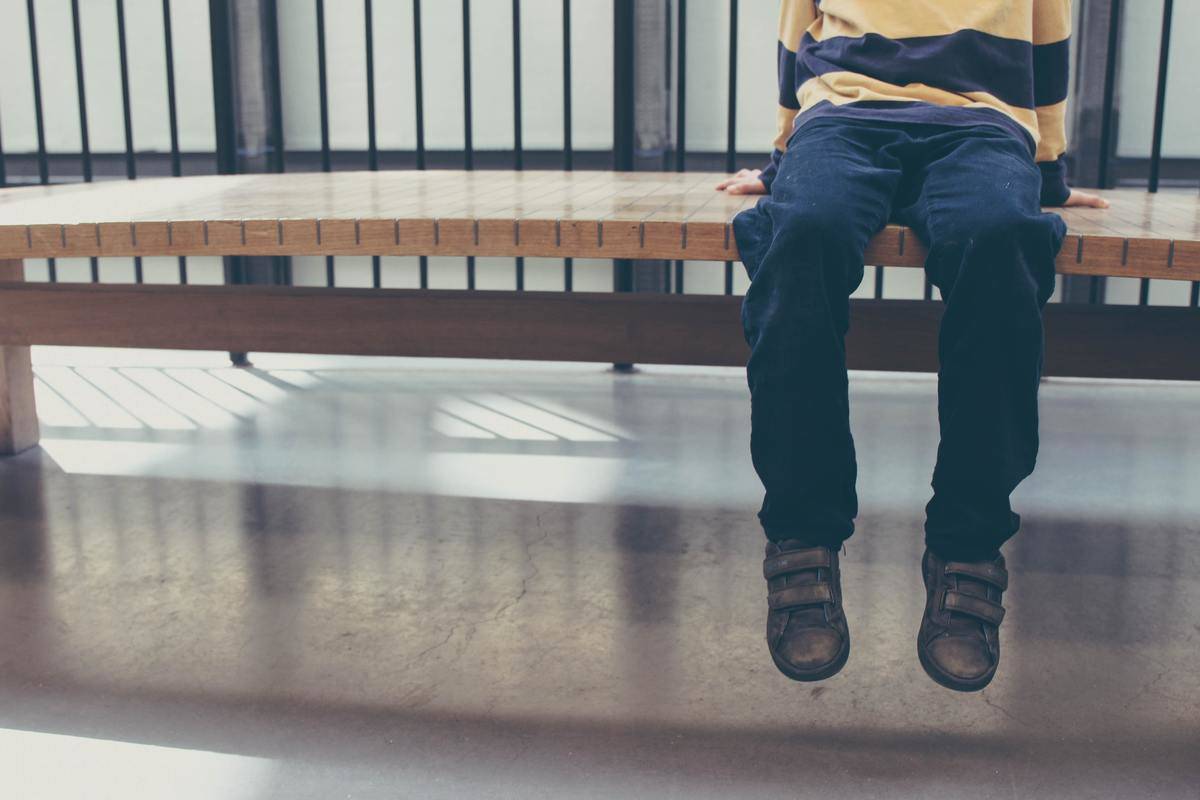 legs of child sitting on the edge of a bench