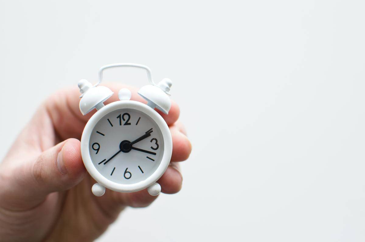 person holding miniature alarm clock