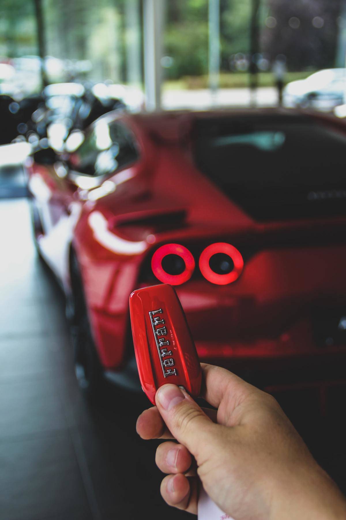 A man holds up keys to a red Ferrari.