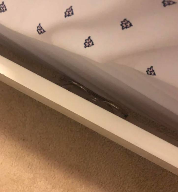 pair of glasses stuck between edge of bedframe and mattress