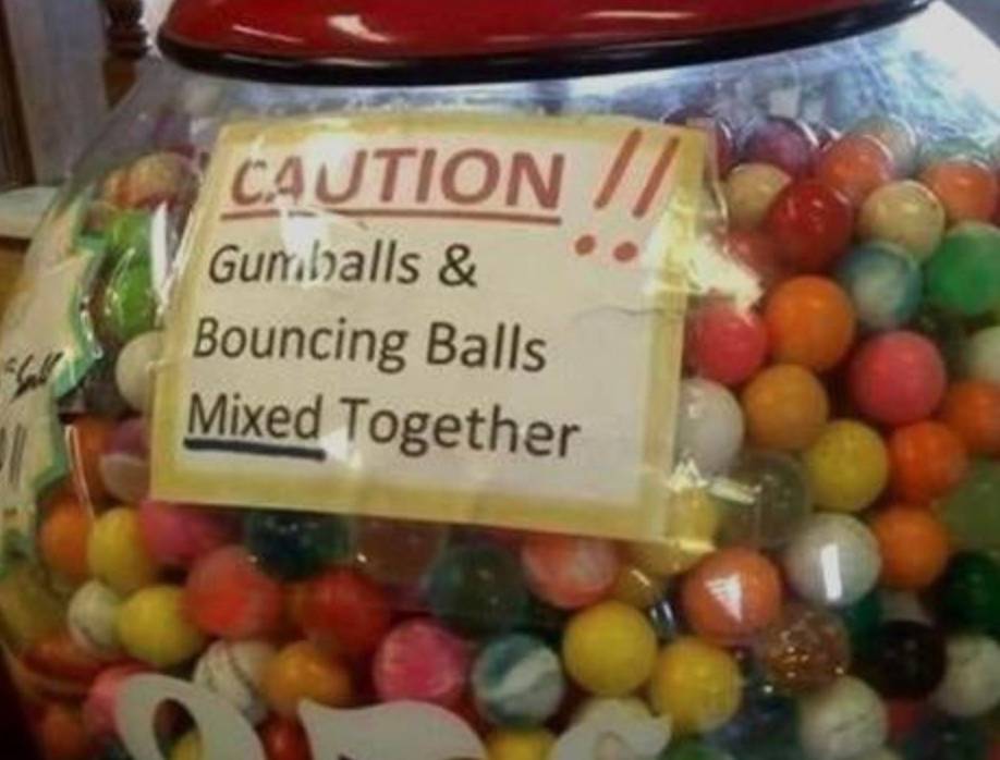 sign on gumball machine reads: CAUTION! Gumballs and Bouncing Balls Mixed Together
