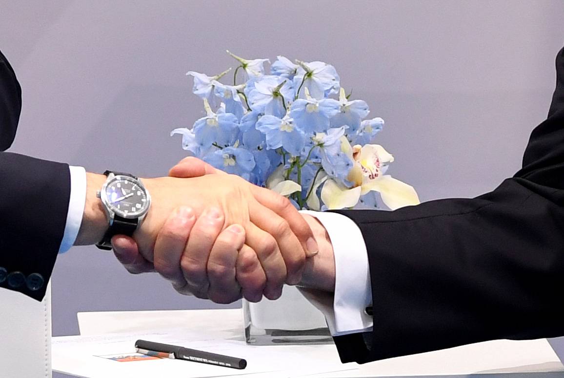 Two people in suits shake hands.