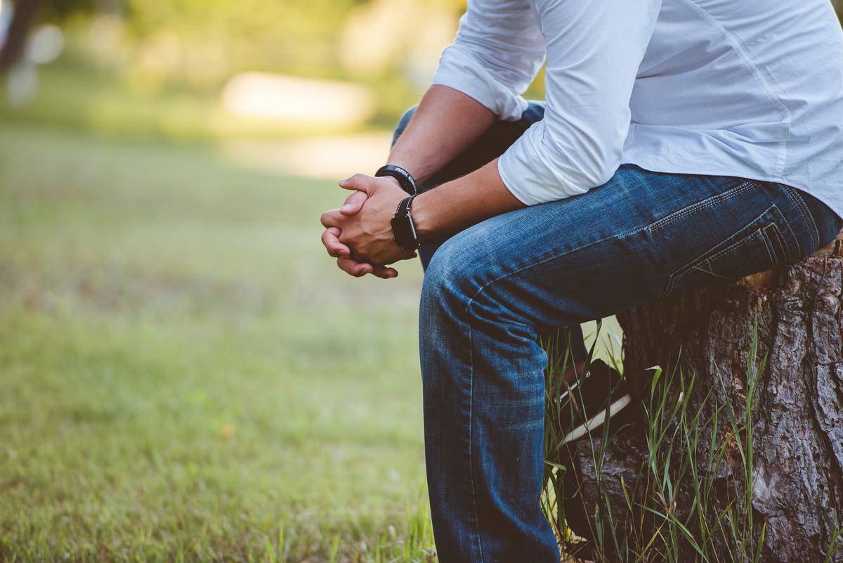 man sitting with his hands clasped, in thought
