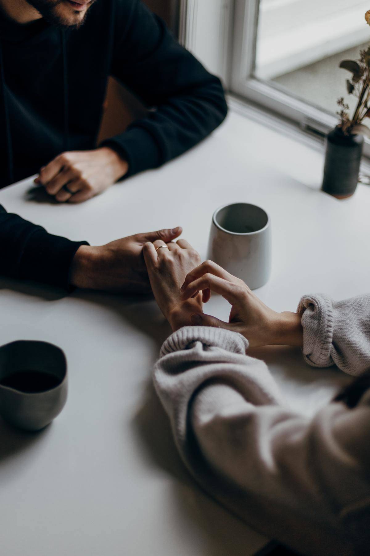 man holding hands out across table for woman to hold
