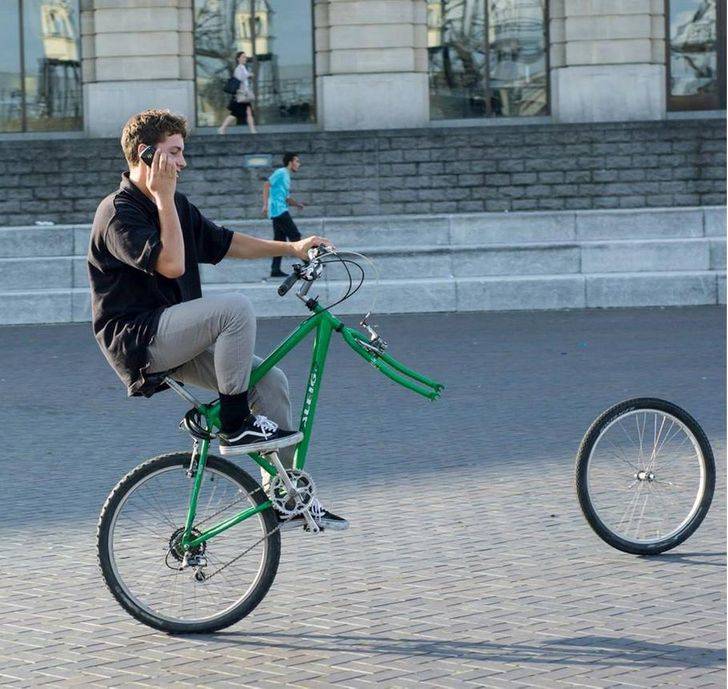 man on bicycle doing a wheelie loses front wheel