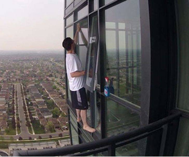 Person cleaning window on high rise building without any safety harness