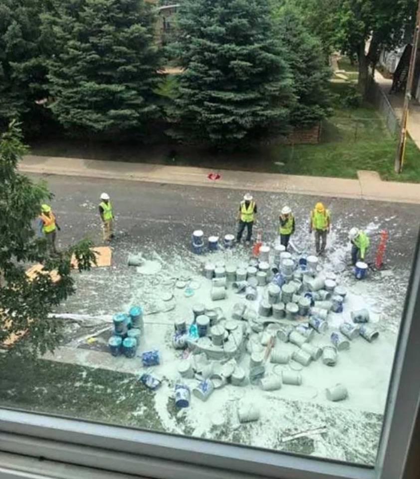 group of construction workers looking at several huge containers of paint spilled on the ground