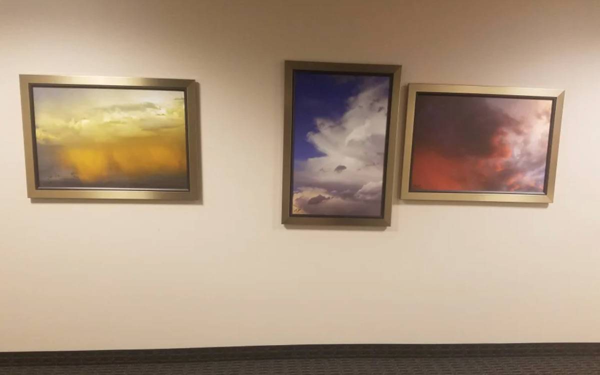 paintings hung on wall in a weird formation and unevenly