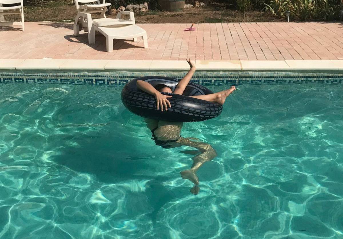someone falling through a pool floaty in the pool 