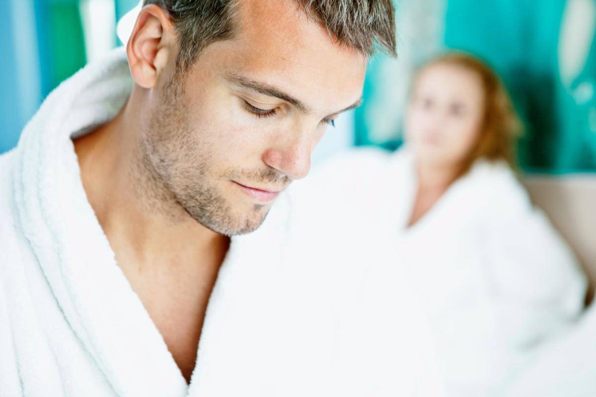 close up of man looking upset with woman is blurred in the background