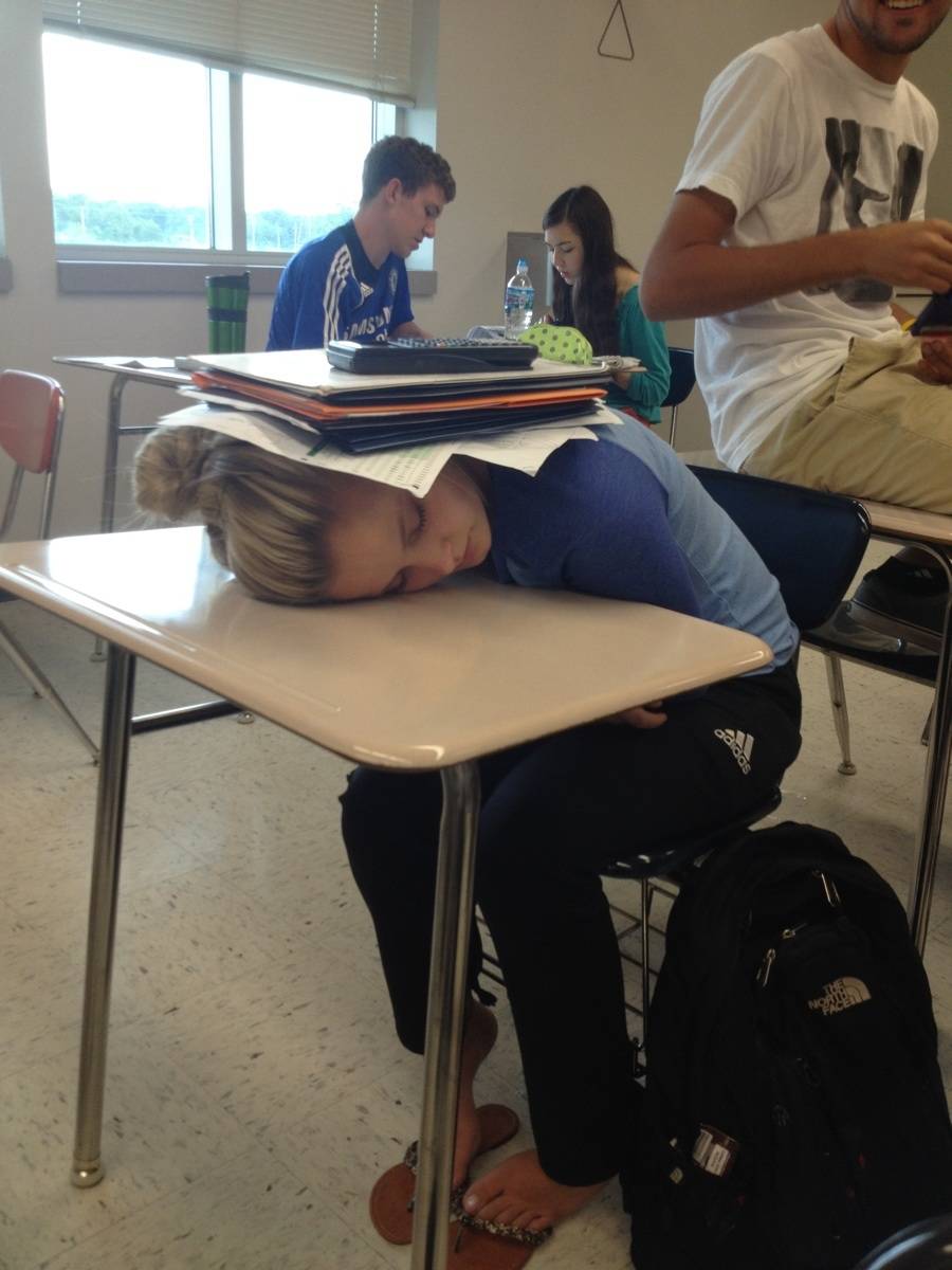 someone sleeping on their desk with a pile of papers and a calculator on them 