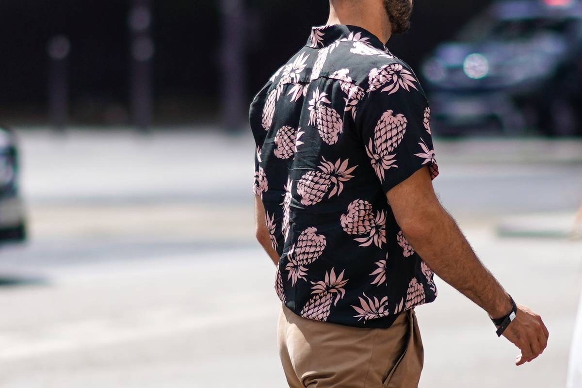 A guest wears a black shirt with pink pineapples pattern, camel pants, outside Jil Sander, during Paris Fashion Wee