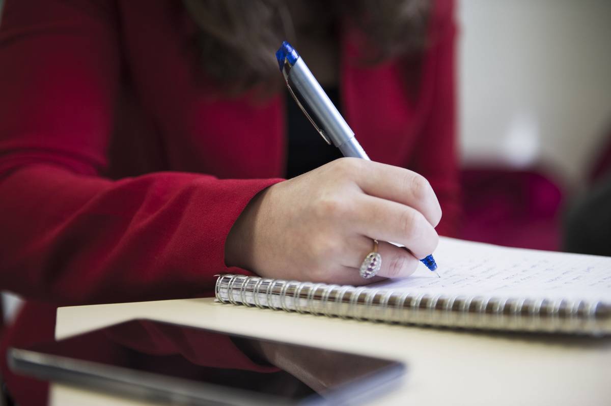 A woman writes notes during a meeting.