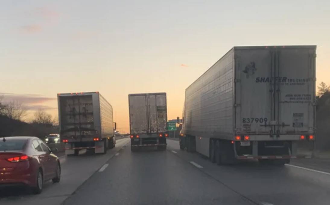 transport trucks all side by side across all three highway lanes