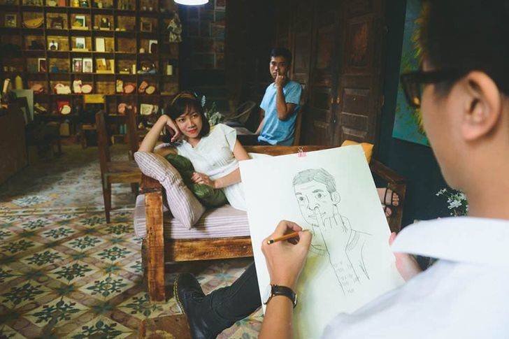 woman lying on a couch as man draws the dude picking his nose behind her