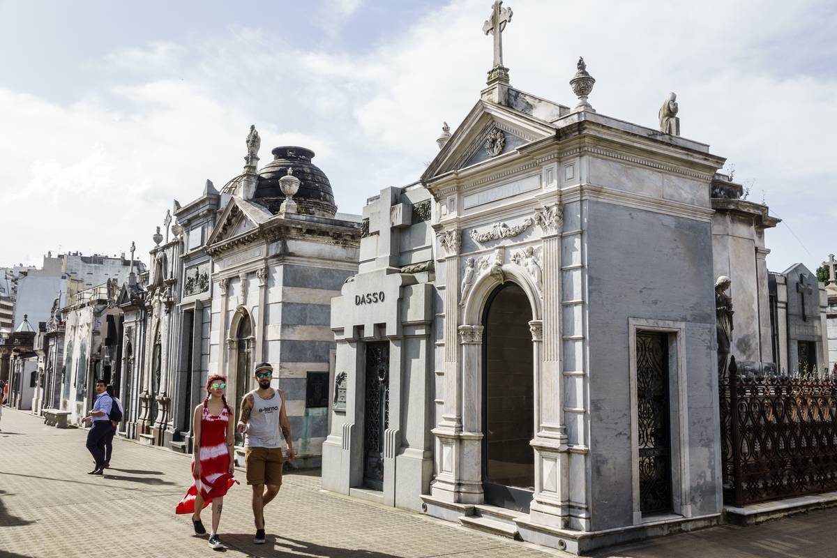 A couple walks past Cementerio de la Recoleta.