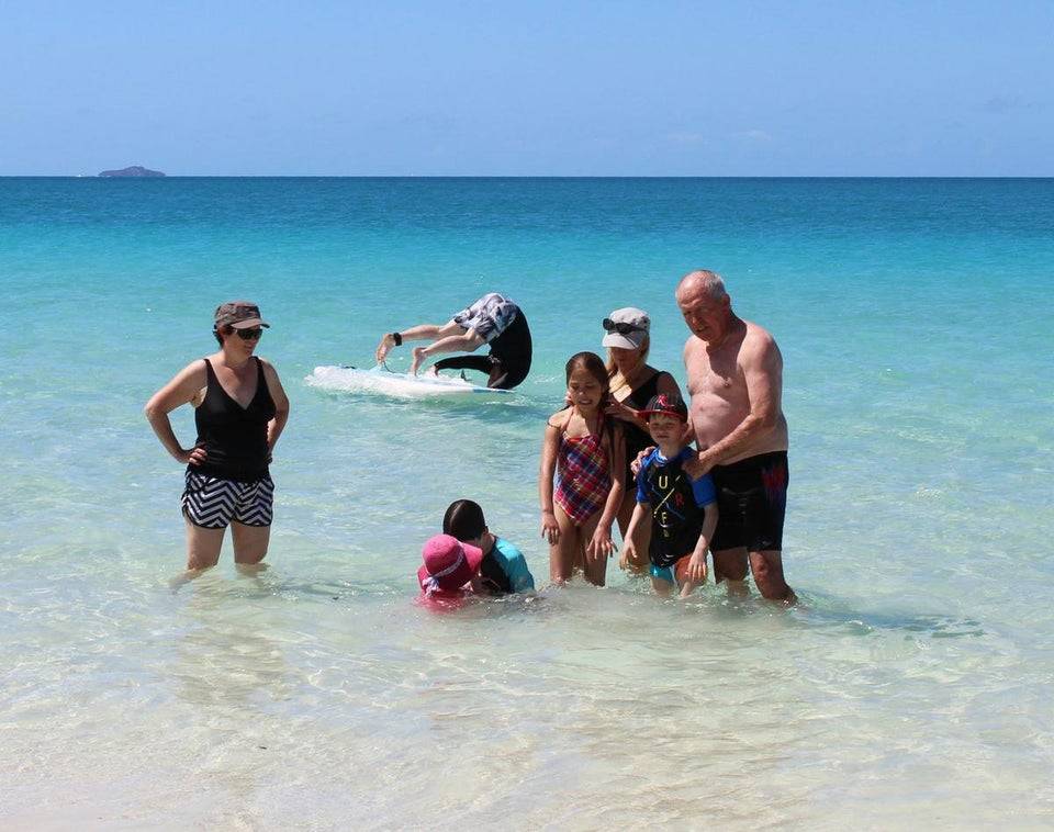 guy flipping in ocean in background of family photo 