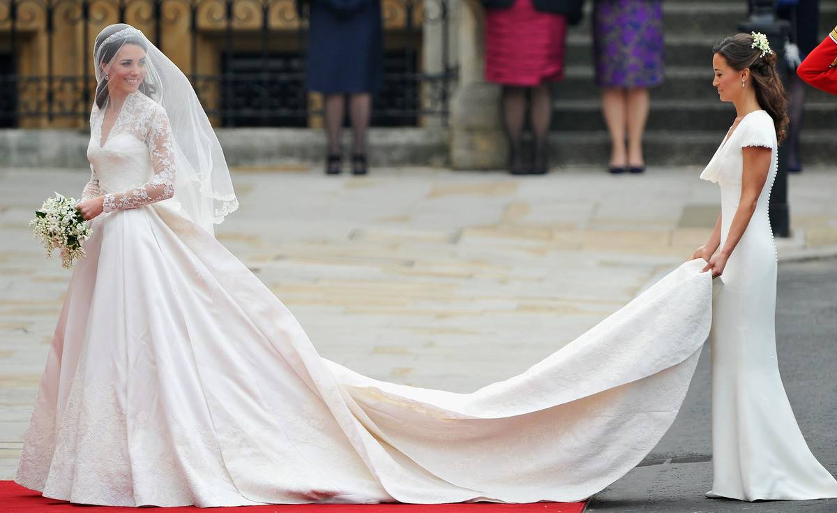 Catherine Middleton waves to the crowds as her sister and Maid of Honour Pippa Middleton holds her wedding dress.