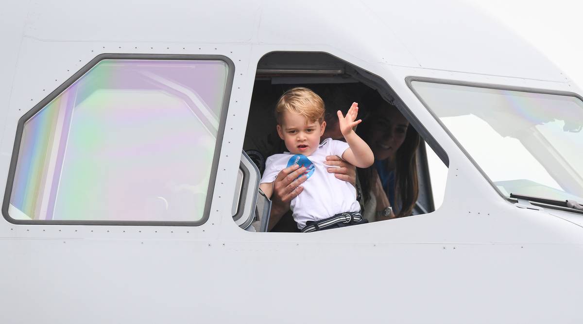 Prince George waves from the cockpit of an airplane.