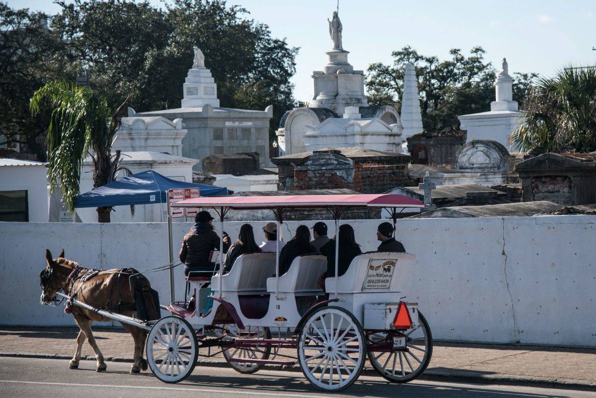 A horse-drawn carriage passes St. Louis cemetery, New Orleans.