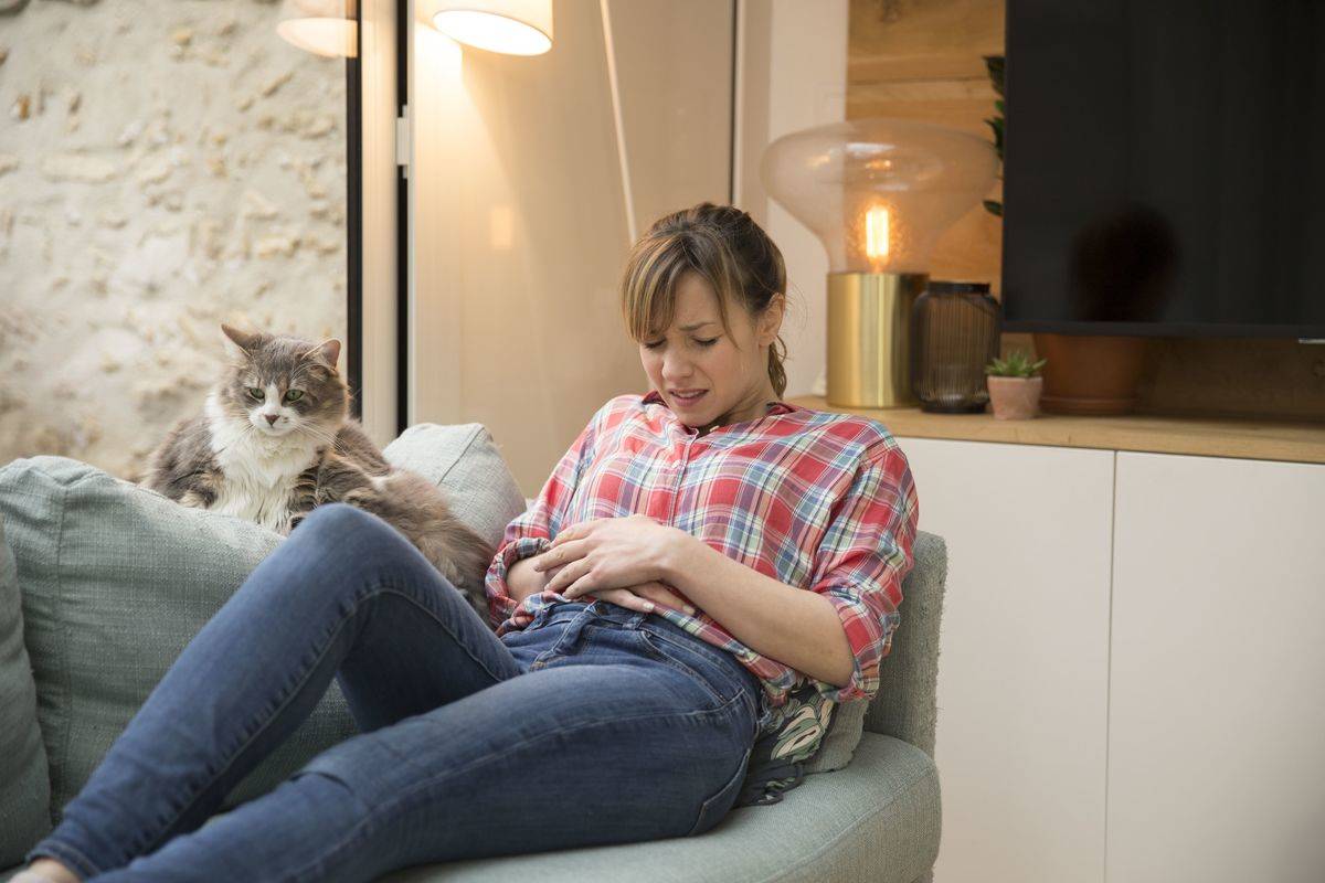 A woman clutches her abdomen in pain.