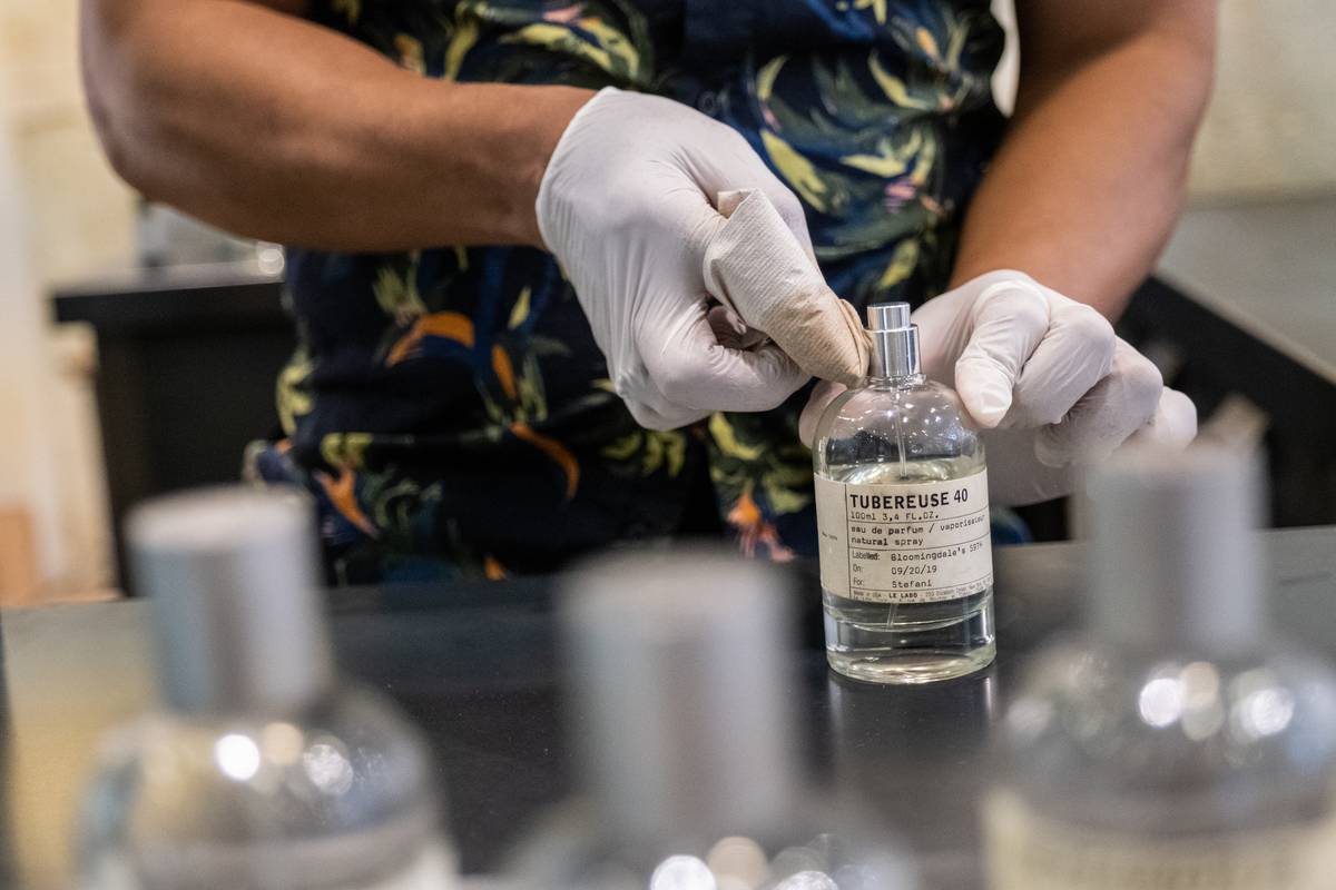 An employee disinfects a perfume bottle top at the Estee Lauder brand Le Labo counter at Bloomingdale's Inc. flagship department story in New York