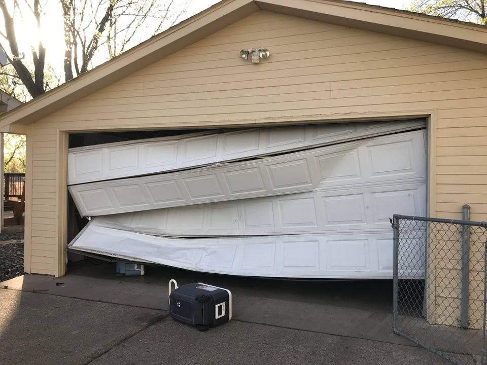 broken crumpled garage door after someone rammed into it with car