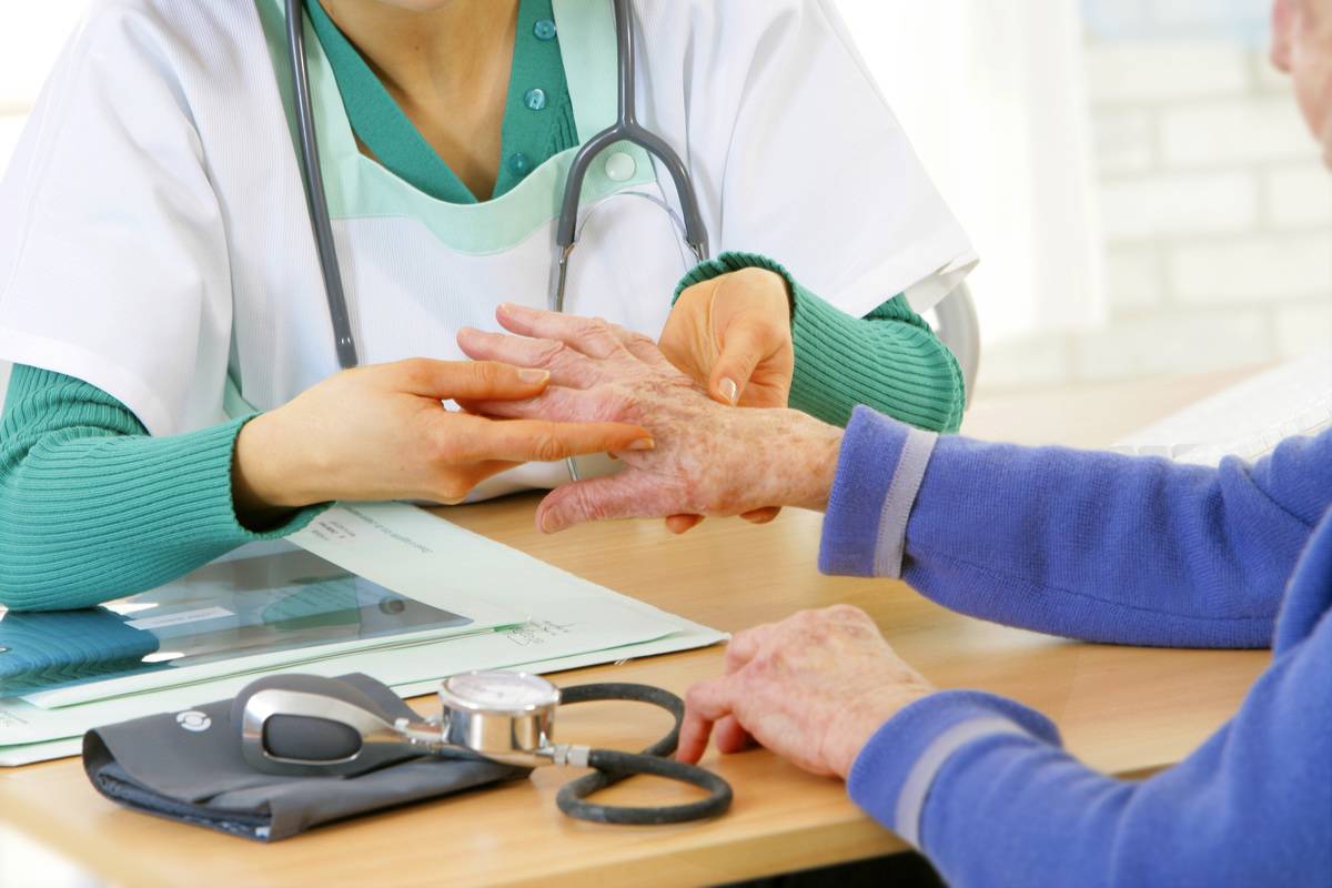 A doctor examines an elderly woman's hands.