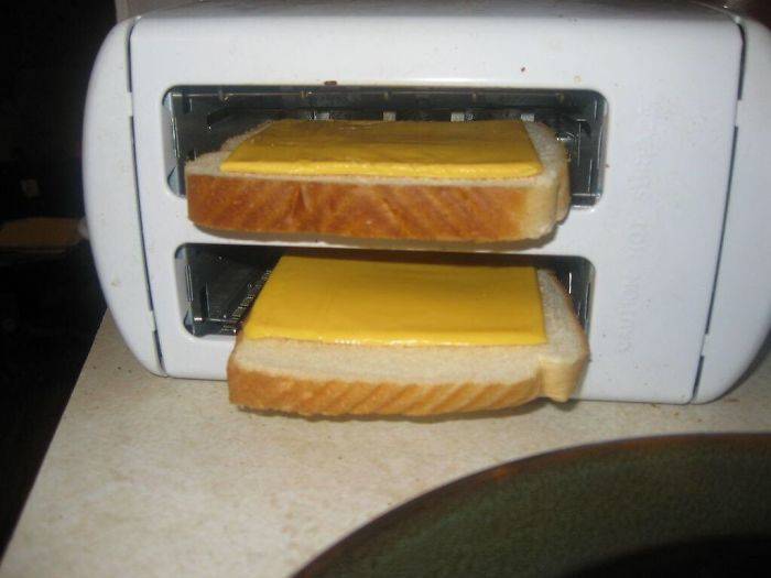 toaster on its side with bread with sliced cheese in it
