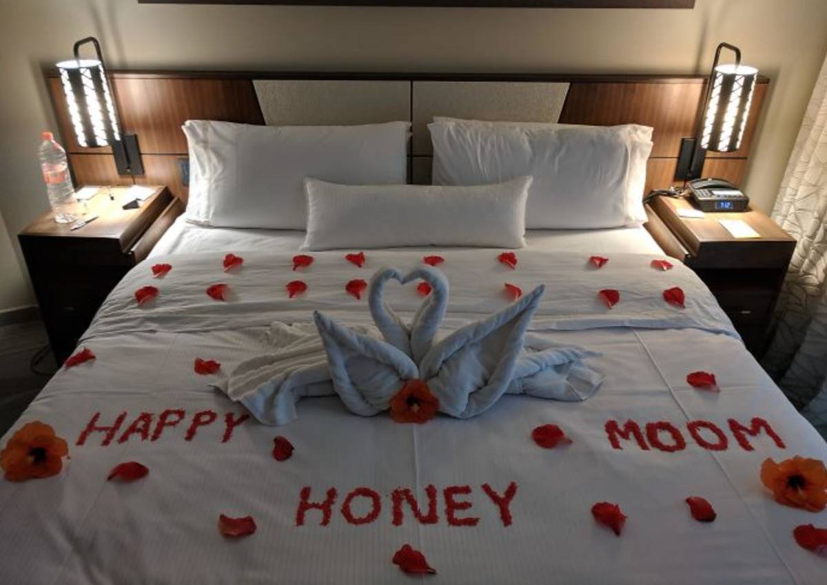 bed laid with rose petals that spell out happy honey moom