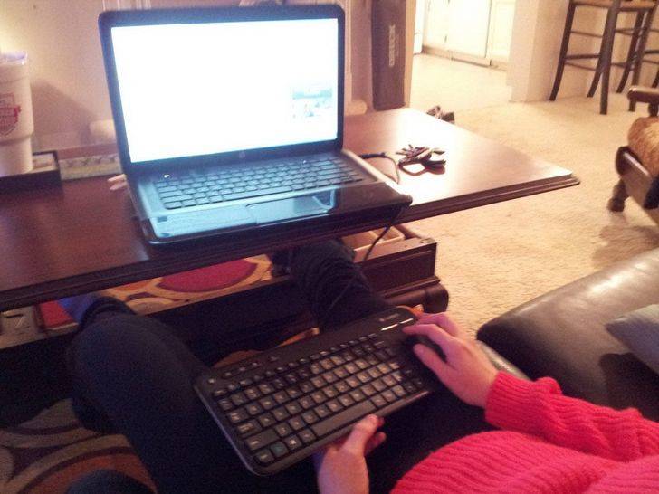 keyboard on lap in front of laptop on desk