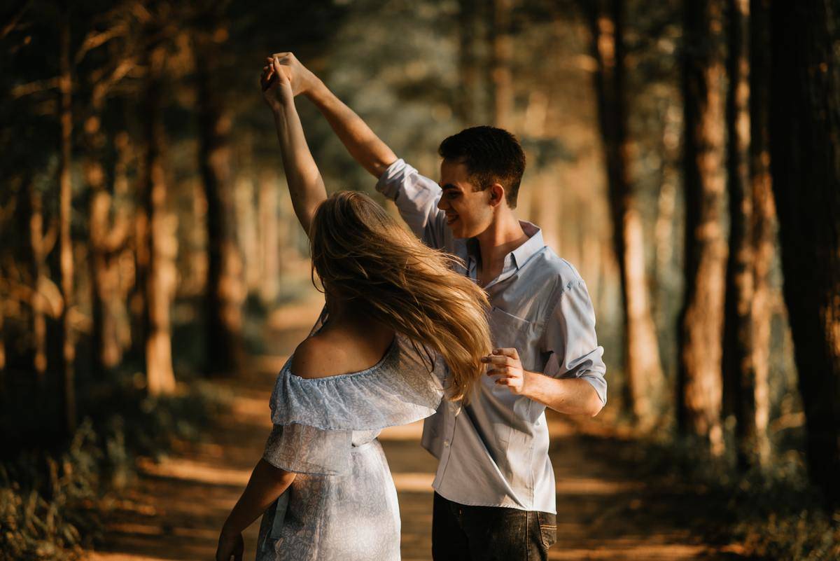 man twirls woman in the woods