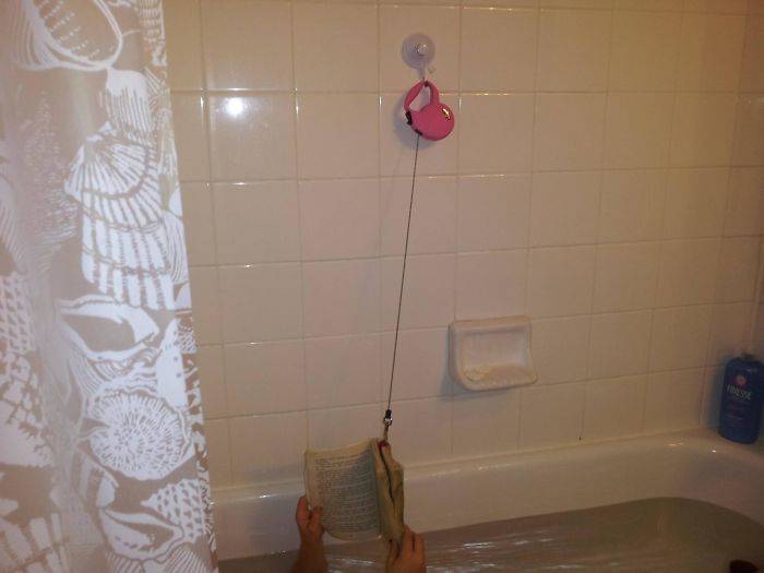 Person reading in bath with book tied to a dog leash so it doesn't fall in