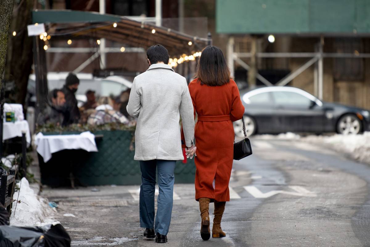A couple wearing gloves holds hands while walking in the West Village on Valentine's Day on February 14, 2021