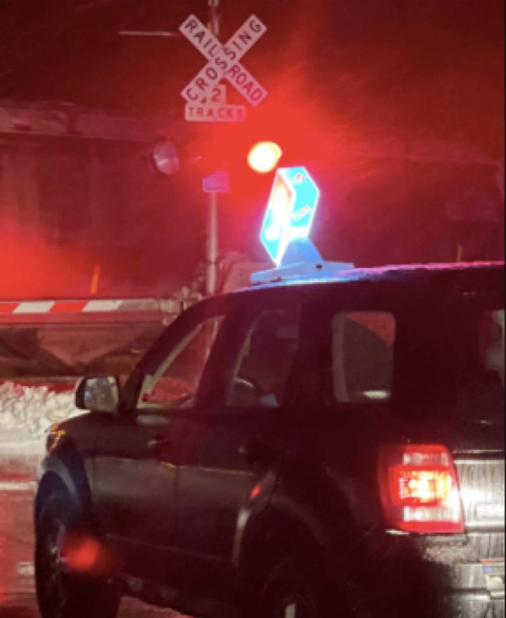 domino's delivery car stuck behind a railway crossing