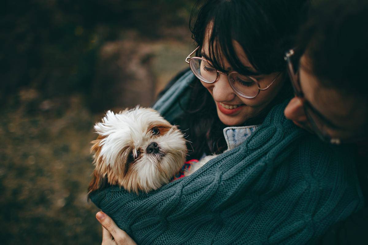 couple holding their dog smiling at them