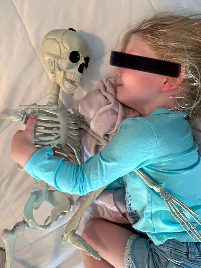 Kid cuddling skeleton toy