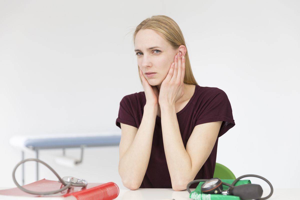 A woman with tinnitus clutches her ears in pain.