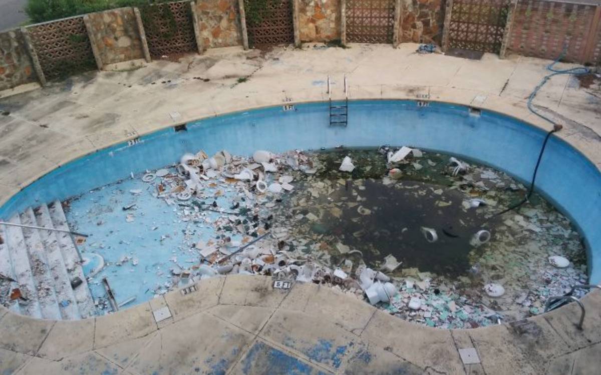 nearly drained swimming pool full of broken toilets