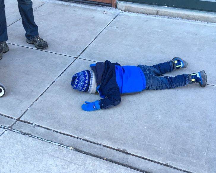 kid all in blue lying facedown on the sidewalk